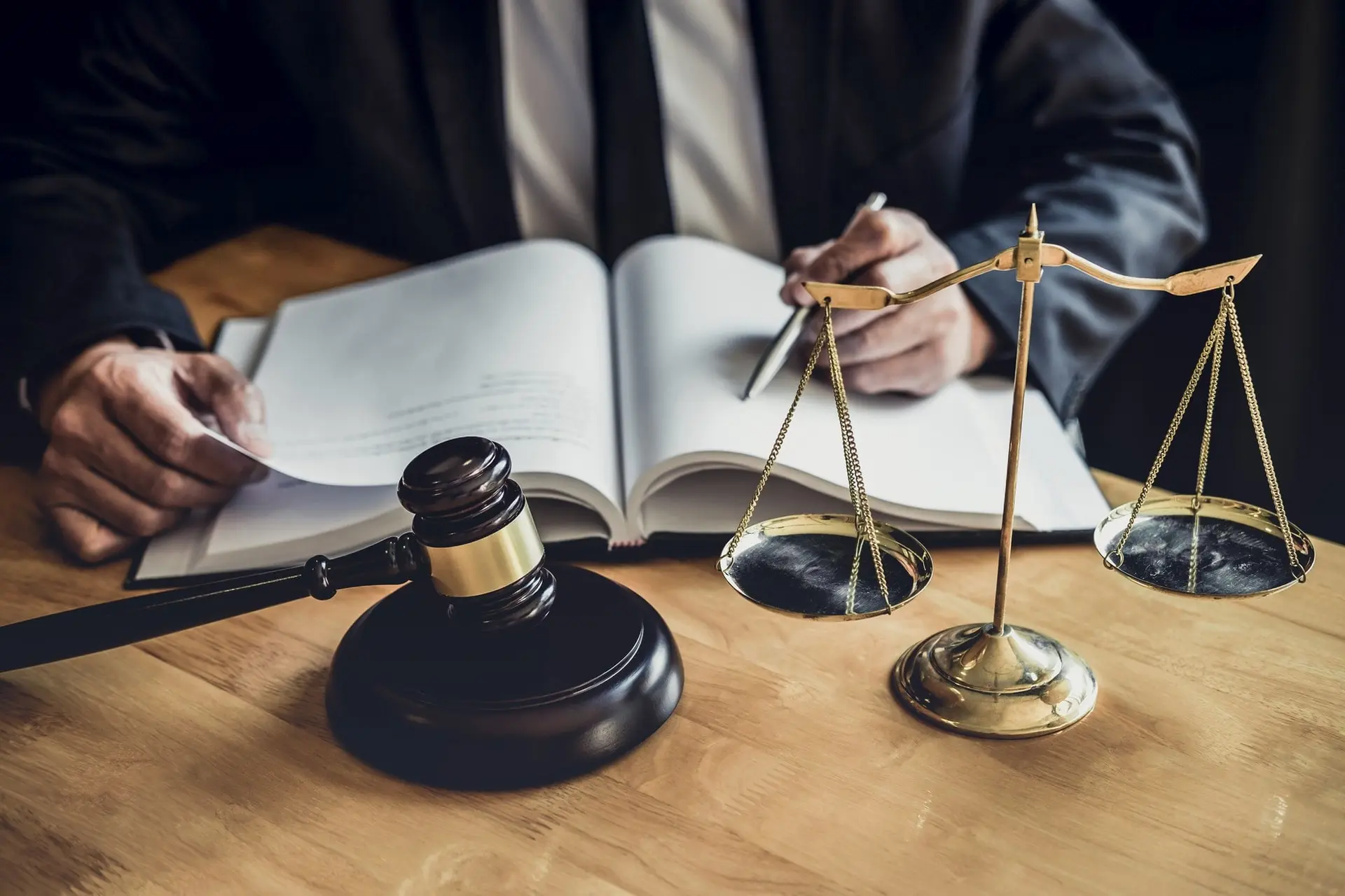 Attorney reviewing a case file beside a gavel and scales of justice