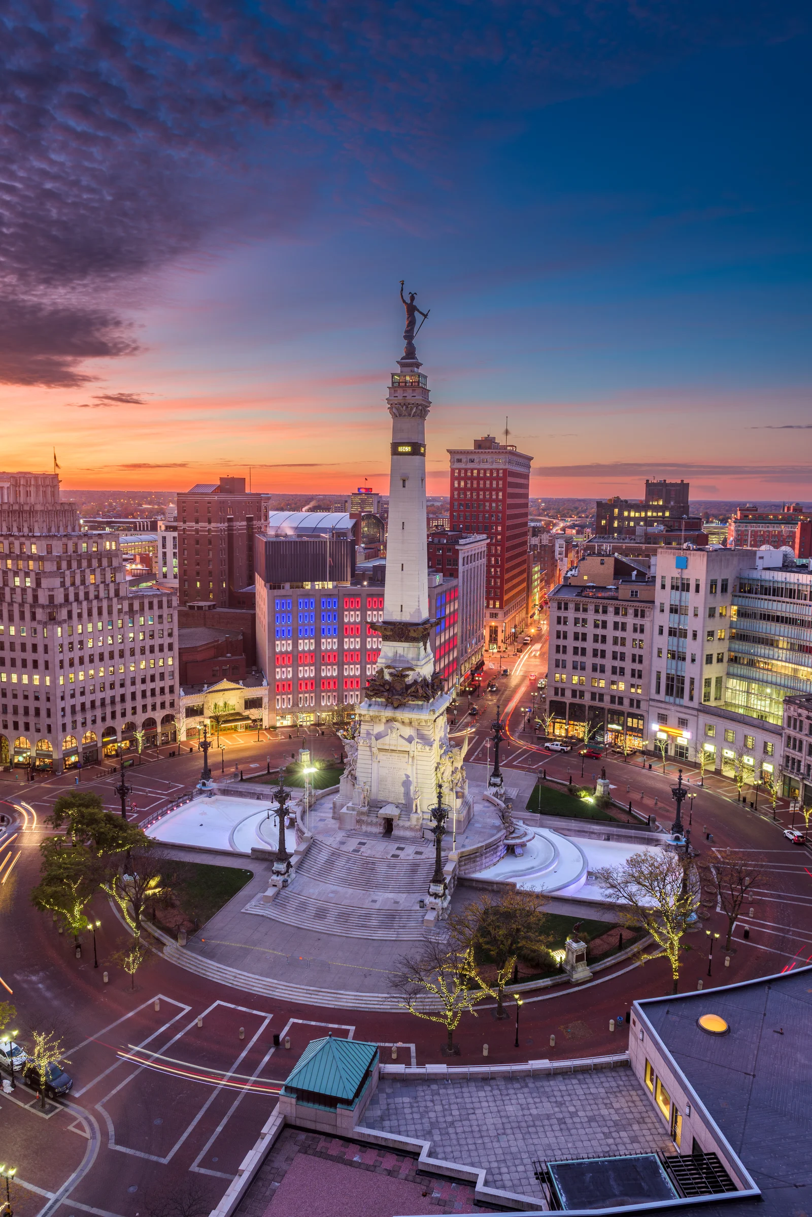 Indianapolis Monument Circle at sunset, showcasing the Soldiers and Sailors Monument surrounded by city buildings and vibrant sky colors, symbolizing the historical significance and community of Northwest Indiana and the Chicagoland area.