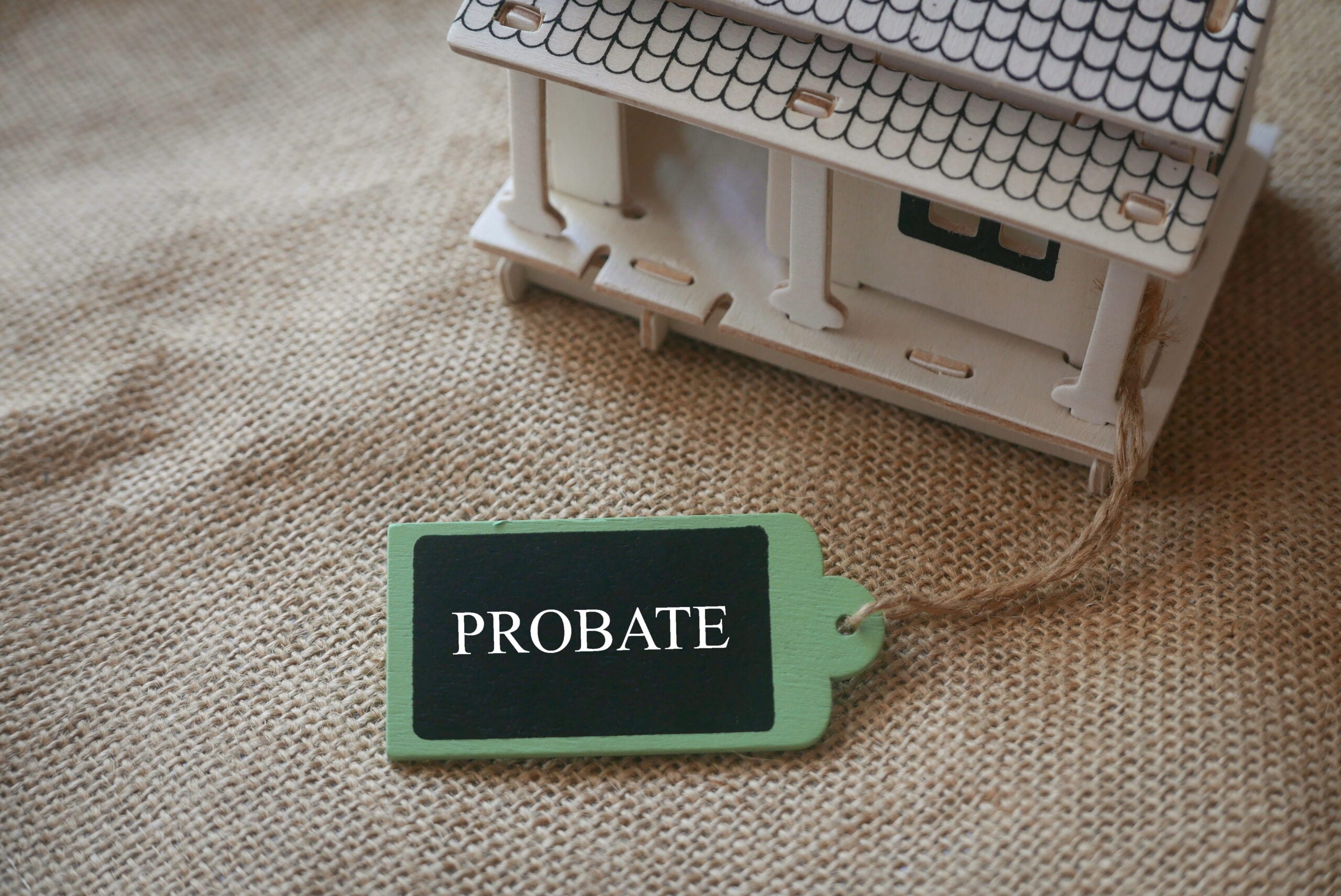 Wooden toy house with a green tag labeled "PROBATE," symbolizing estate management and legal processes related to probate law.
