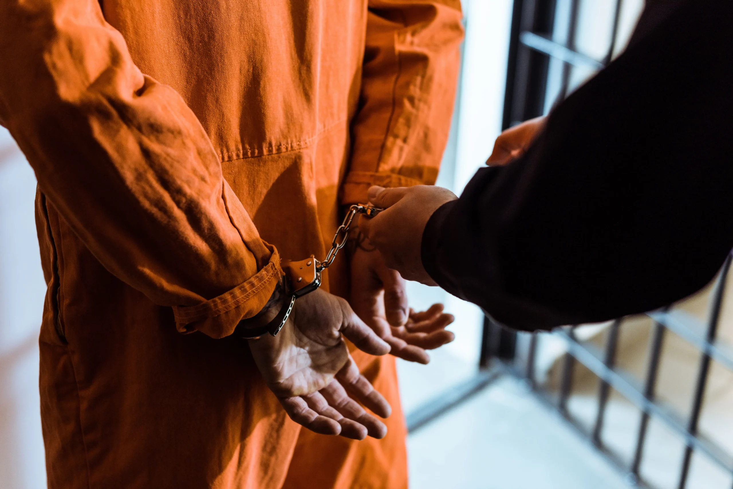 Prison officer handcuffing an individual in an orange jumpsuit, illustrating criminal defense context for legal services in Northwest Indiana and the Chicagoland area.